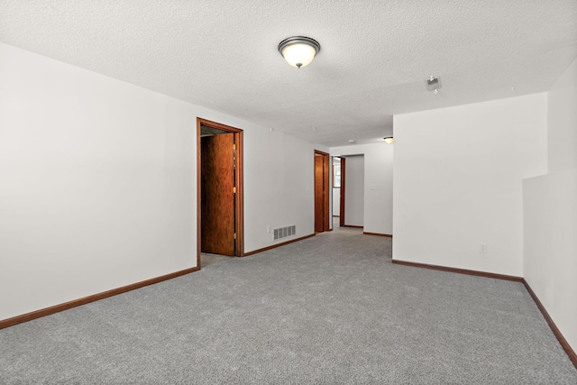 spare room featuring carpet, baseboards, visible vents, and a textured ceiling