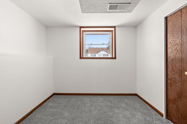 carpeted empty room featuring baseboards, visible vents, and a textured ceiling