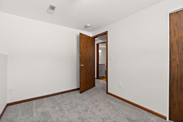 carpeted empty room with visible vents, baseboards, and a textured ceiling