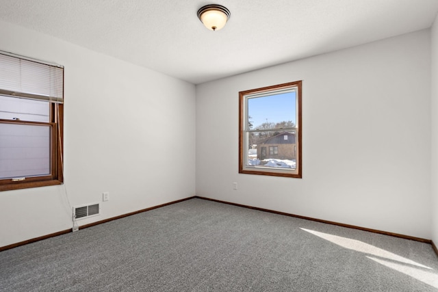 carpeted spare room featuring baseboards and visible vents