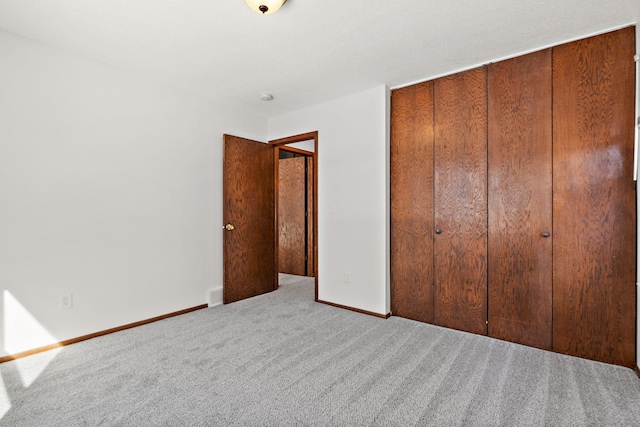 unfurnished bedroom featuring a closet, visible vents, baseboards, and carpet floors