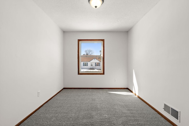 carpeted empty room with baseboards, visible vents, and a textured ceiling