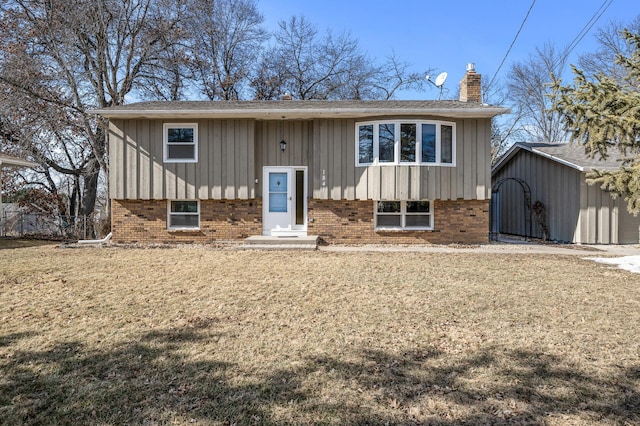 split foyer home with brick siding, fence, a front lawn, board and batten siding, and a chimney