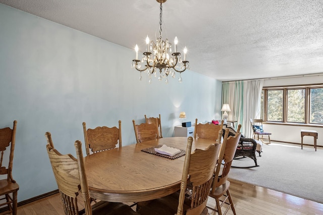 dining space with a chandelier, baseboards, a textured ceiling, and light wood finished floors