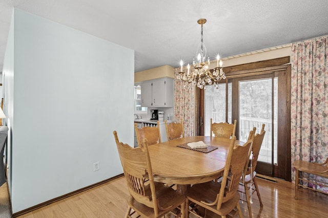 dining area featuring baseboards, light wood finished floors, and a notable chandelier