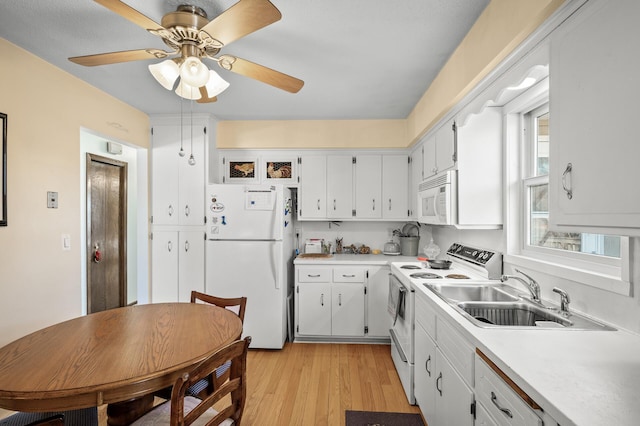 kitchen featuring white appliances, a sink, white cabinetry, light wood-style floors, and light countertops