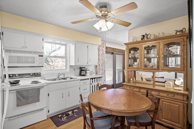 kitchen featuring a textured ceiling, white appliances, a sink, white cabinetry, and light countertops