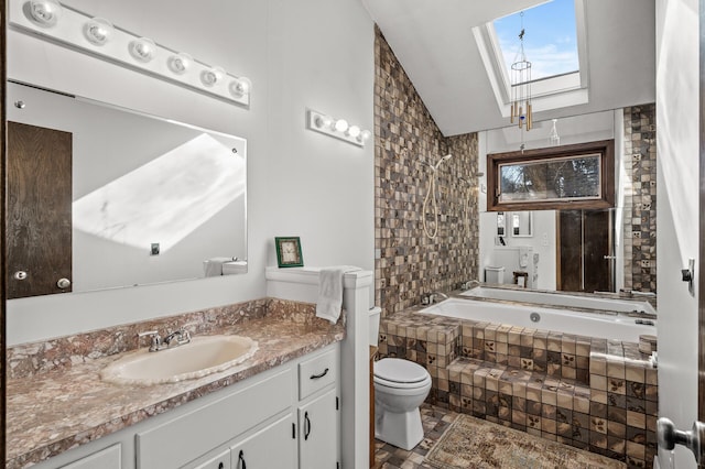 bathroom featuring tiled shower / bath, vaulted ceiling with skylight, vanity, and toilet