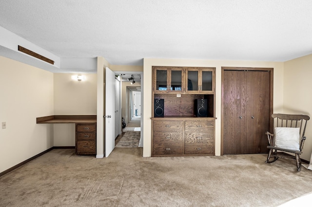 unfurnished bedroom with light colored carpet, a textured ceiling, and baseboards