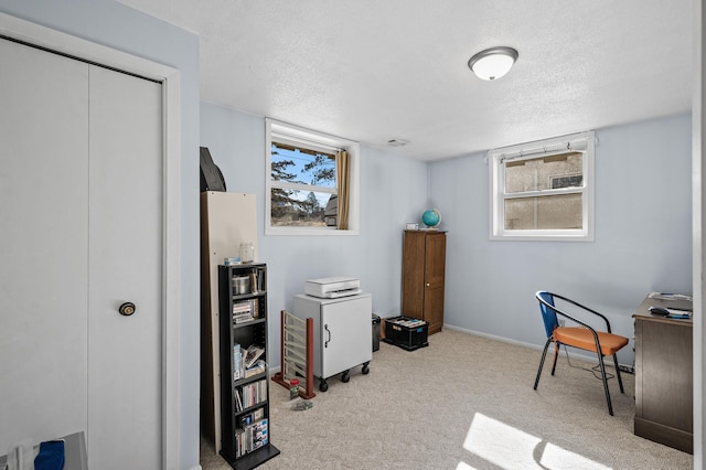 carpeted office space featuring a textured ceiling and baseboards