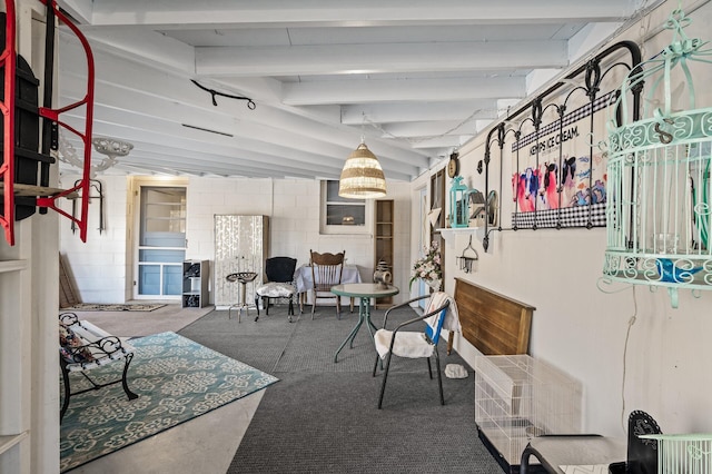 interior space featuring concrete block wall and beam ceiling