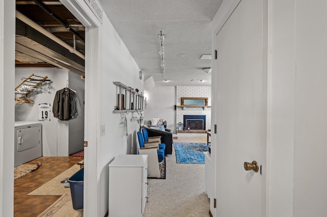 hallway featuring washer / dryer, carpet, a textured ceiling, and track lighting