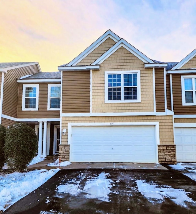 townhome / multi-family property featuring stone siding and an attached garage