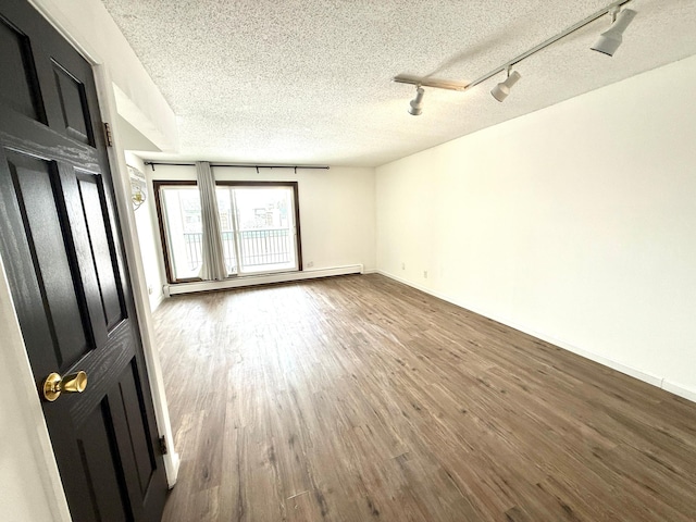 spare room featuring a textured ceiling, baseboards, baseboard heating, and wood finished floors