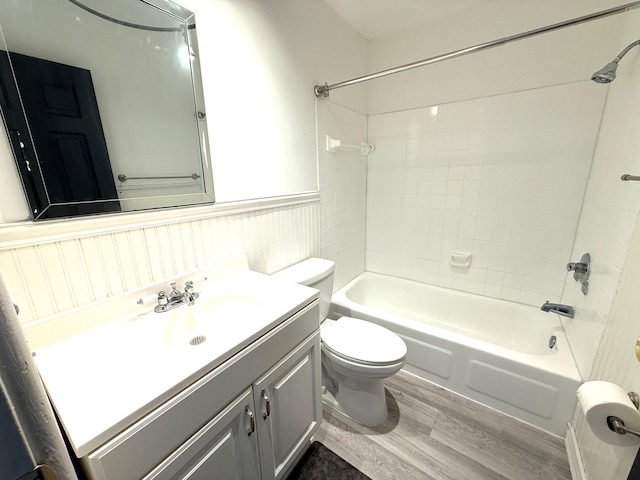 full bathroom with wainscoting, toilet, wood finished floors, vanity, and washtub / shower combination