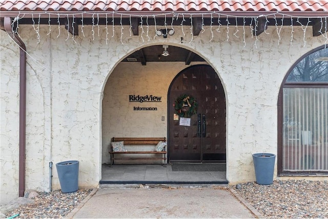 doorway to property featuring a tile roof and stucco siding