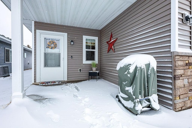 snow covered property entrance with a porch and central AC unit