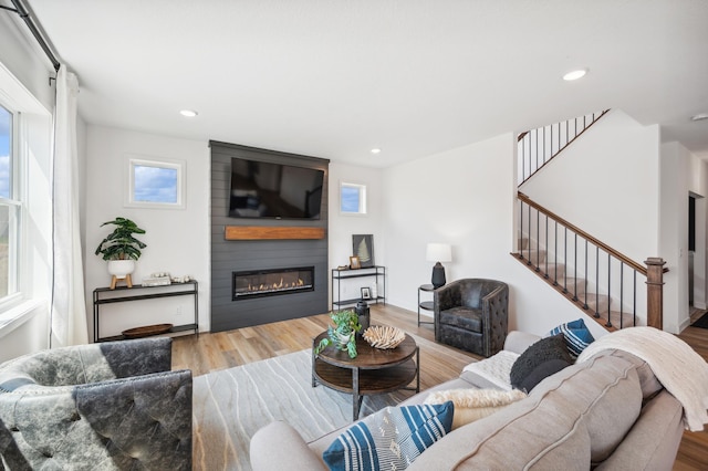 living room featuring stairs, a fireplace, wood finished floors, and recessed lighting