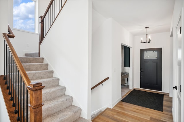 foyer with a chandelier, light wood-type flooring, and baseboards