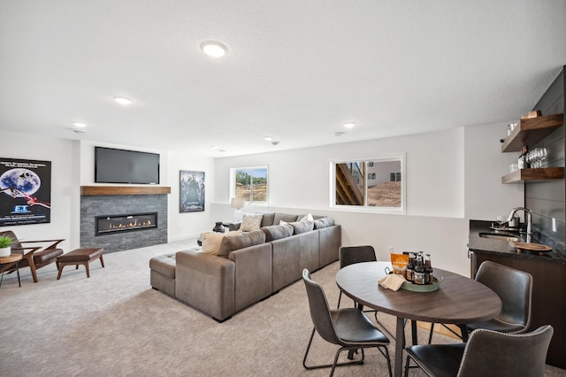 living area with recessed lighting, a glass covered fireplace, light colored carpet, and wet bar