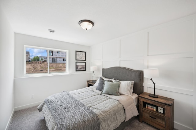 bedroom with carpet floors, a decorative wall, and baseboards