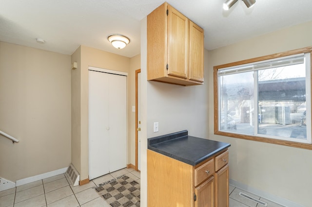 kitchen with dark countertops, light tile patterned flooring, baseboards, and visible vents