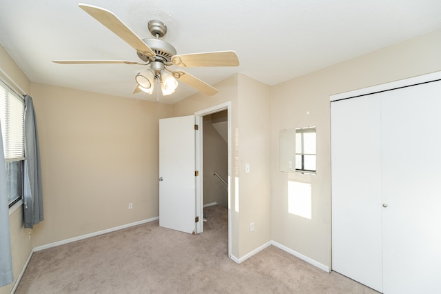 unfurnished bedroom featuring ceiling fan, light colored carpet, a closet, and baseboards