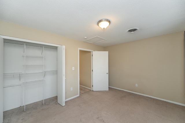 unfurnished bedroom featuring visible vents, light carpet, a closet, baseboards, and attic access