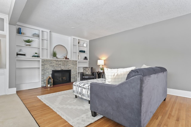 living room with a fireplace, wood finished floors, baseboards, and a textured ceiling