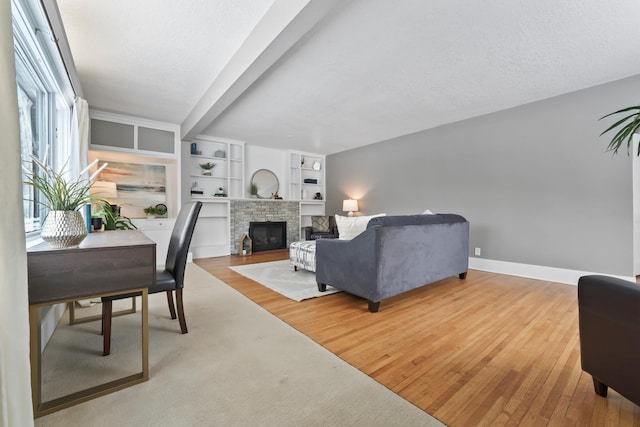 living room featuring wood finished floors, a fireplace, baseboards, and a textured ceiling