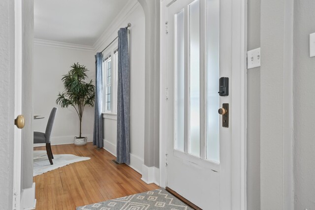 entryway featuring baseboards, crown molding, and light wood finished floors