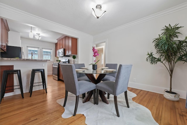 dining area featuring baseboards, light wood-type flooring, and ornamental molding