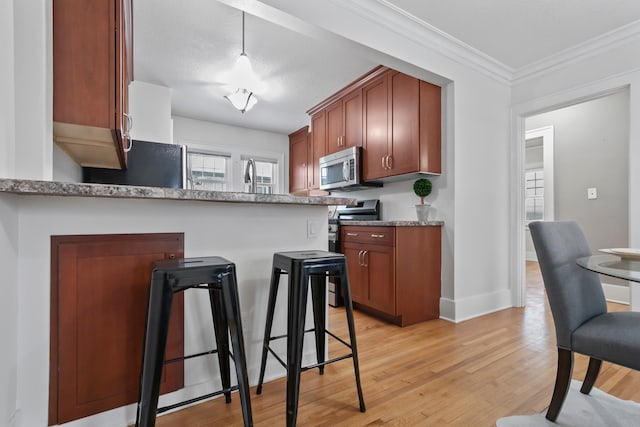 kitchen with stainless steel appliances, plenty of natural light, a breakfast bar area, and light wood-style flooring