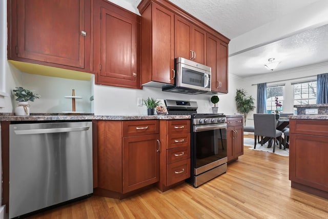 kitchen with crown molding, light wood-style floors, appliances with stainless steel finishes, and a textured ceiling