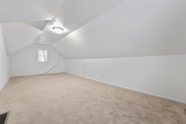 additional living space featuring vaulted ceiling, visible vents, baseboards, and carpet floors