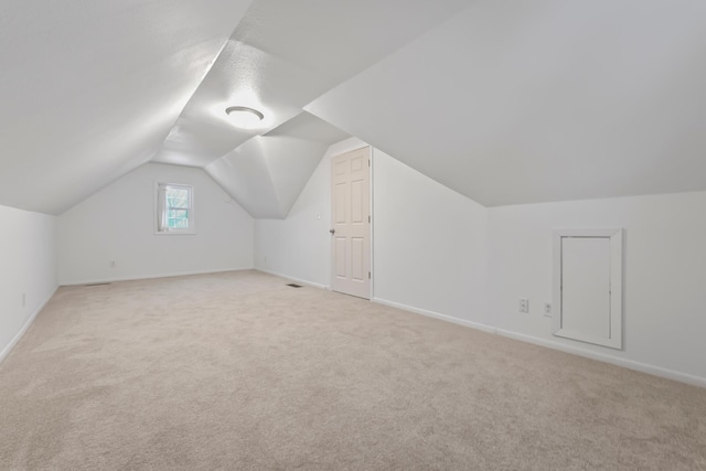 additional living space with lofted ceiling, baseboards, and light carpet