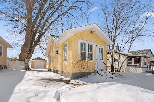 view of front of house with fence, stucco siding, entry steps, an outdoor structure, and a garage