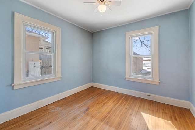 empty room featuring baseboards, ornamental molding, a ceiling fan, and hardwood / wood-style flooring