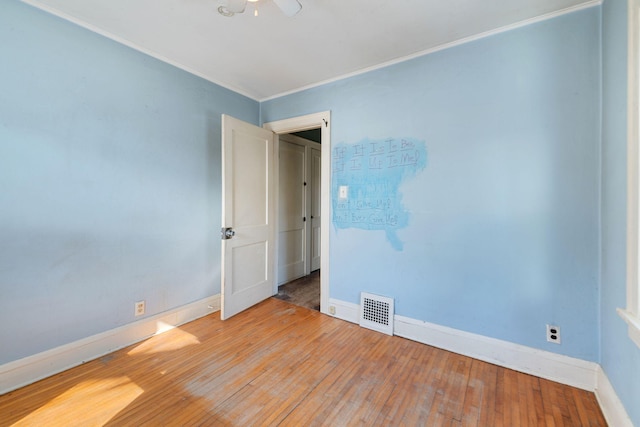 unfurnished room featuring visible vents, ornamental molding, baseboards, and hardwood / wood-style flooring