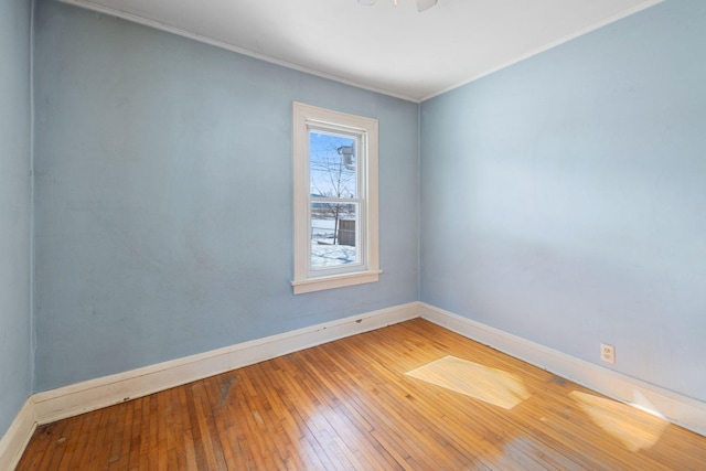 empty room with ornamental molding, baseboards, and hardwood / wood-style floors