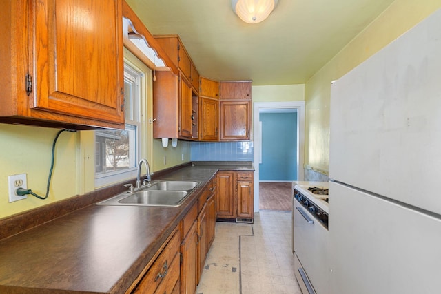 kitchen with dark countertops, tasteful backsplash, brown cabinets, white appliances, and a sink