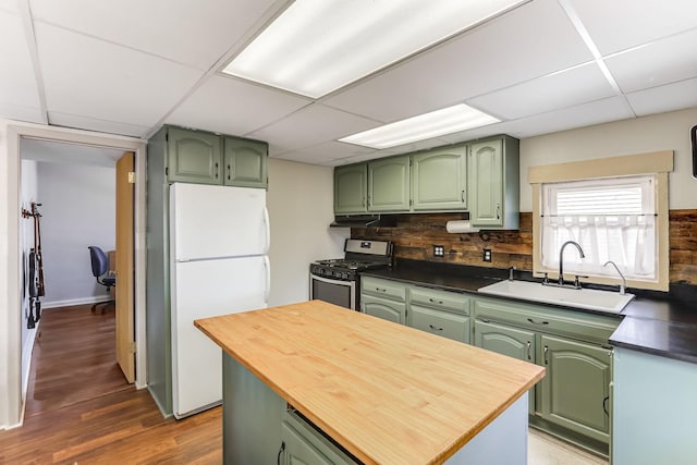 kitchen featuring gas range, freestanding refrigerator, and green cabinetry