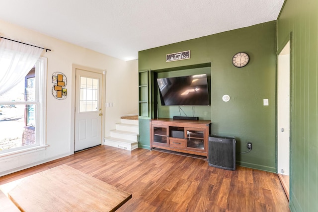 living area with baseboards, a textured ceiling, and wood finished floors