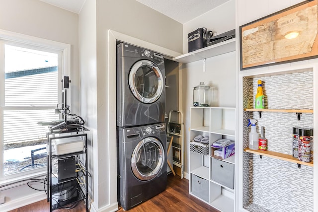 laundry area featuring dark wood-style floors, stacked washer / dryer, plenty of natural light, and laundry area