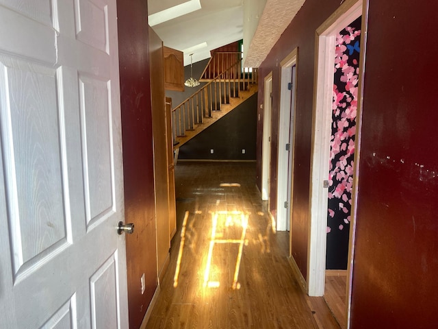 corridor featuring baseboards, stairway, and wood finished floors