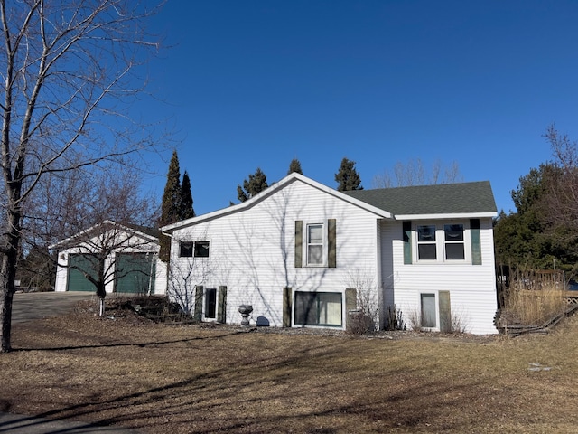 view of front of home with a garage, concrete driveway, a shingled roof, and an outdoor structure