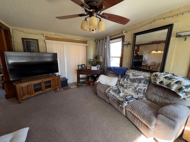 carpeted living area featuring ceiling fan with notable chandelier and a textured ceiling