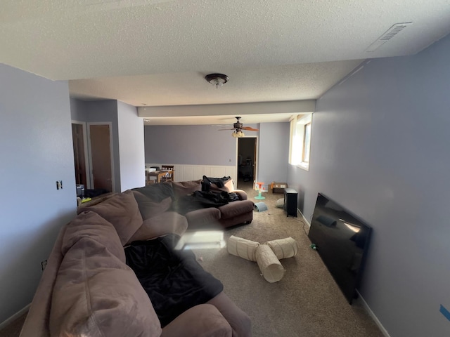 carpeted living area with a textured ceiling, visible vents, and a ceiling fan