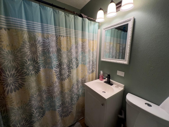 full bath featuring a textured wall, curtained shower, vanity, and toilet