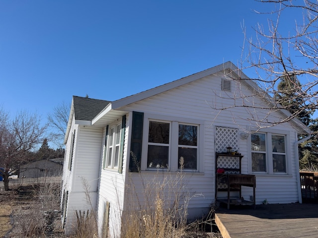 view of side of home featuring a deck and roof with shingles